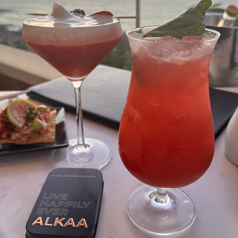 Two cocktails on a table with a scenic background