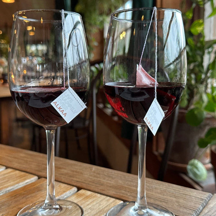 Red wine on a restaurant table with two ALKAA Tagged Sachets 