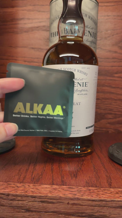 Front of ALKAA Singles Pack in front of Scotch bottle.